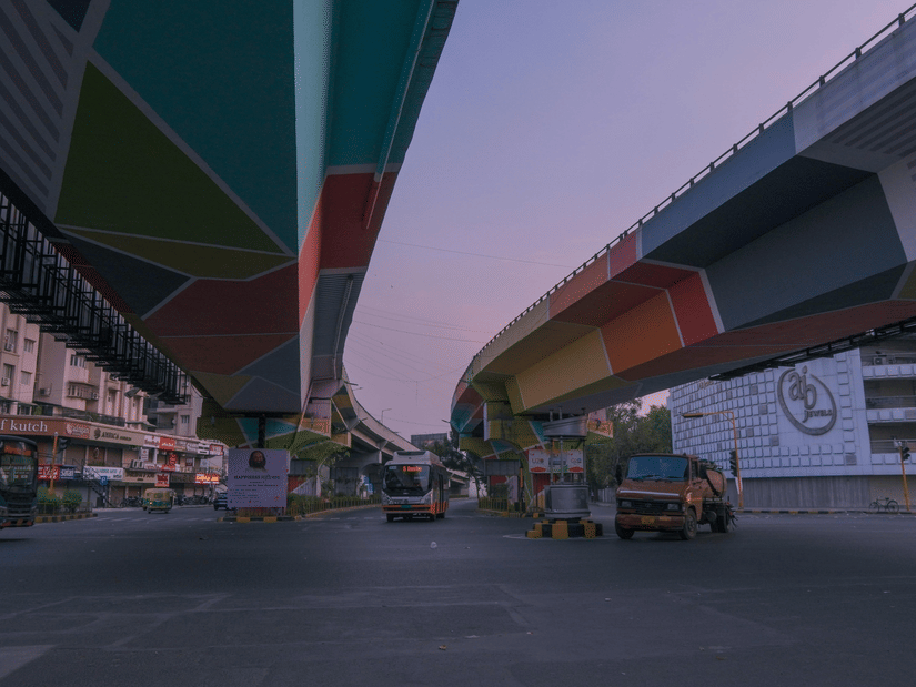 Low-angle view of 2 flyovers with underpasses painted in vibrant geometric colours at dusk.