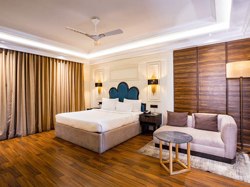 One of the rooms at Wedlock Greens Hotel & Resort Dhanbad features a double bed with a sofa, ideal for a comfortable stay in a couple room in Dhanbad