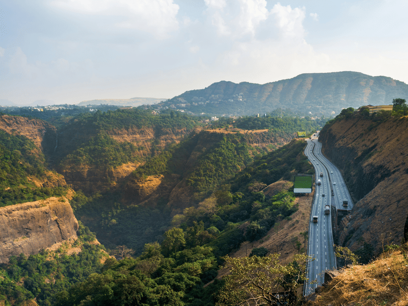 The road to Rajmachi Point featuring a winding highway cutting through green hills and rugged terrain.