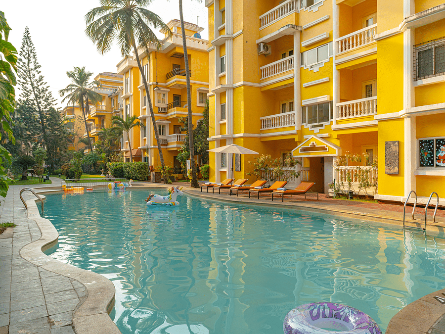 An image of an outdoor swimming pool framed by yellow buildings.