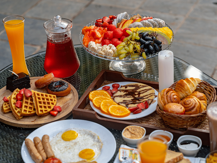 An image of a dining table showcasing beverages, fruits, snacks, and baked goods.