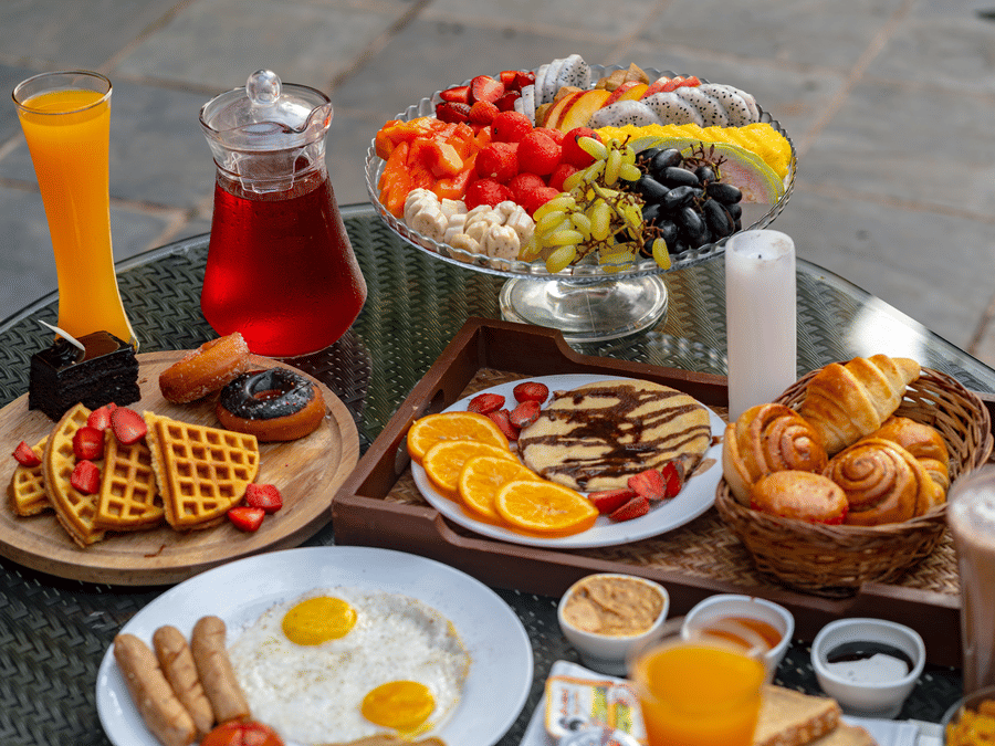 An image of a dining table showcasing beverages, fruits, snacks, and baked goods.