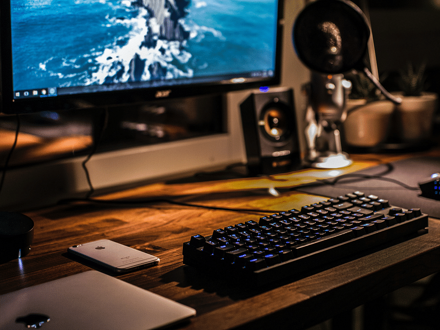 A monitor displaying a screen, a keyboard, speakers, a microphone, and a laptop.