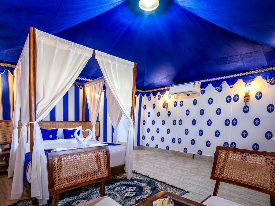 Decorated tent at Buena Vista Luxury Garden Spa Resort with a four-poster bed, blue and white striped walls, and comfortable seating.