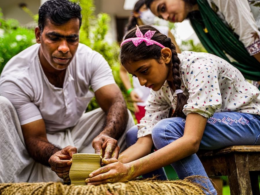 A pottery instructor teaching the art to a girl who is in working on a pot - Heritage Village, Goa