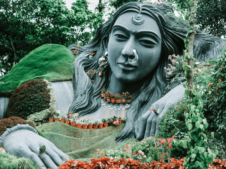 Close-up of the famous Yakshi statue at Malampuzha Gardens surrounded by greenery.