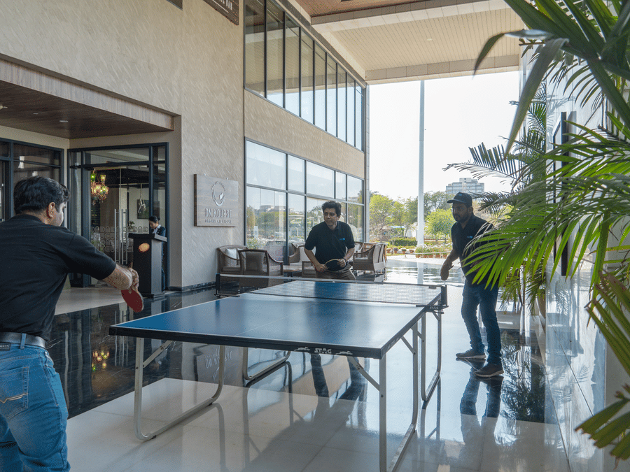 Three people playing table tennis in a modern indoor area at Karma Lakelands