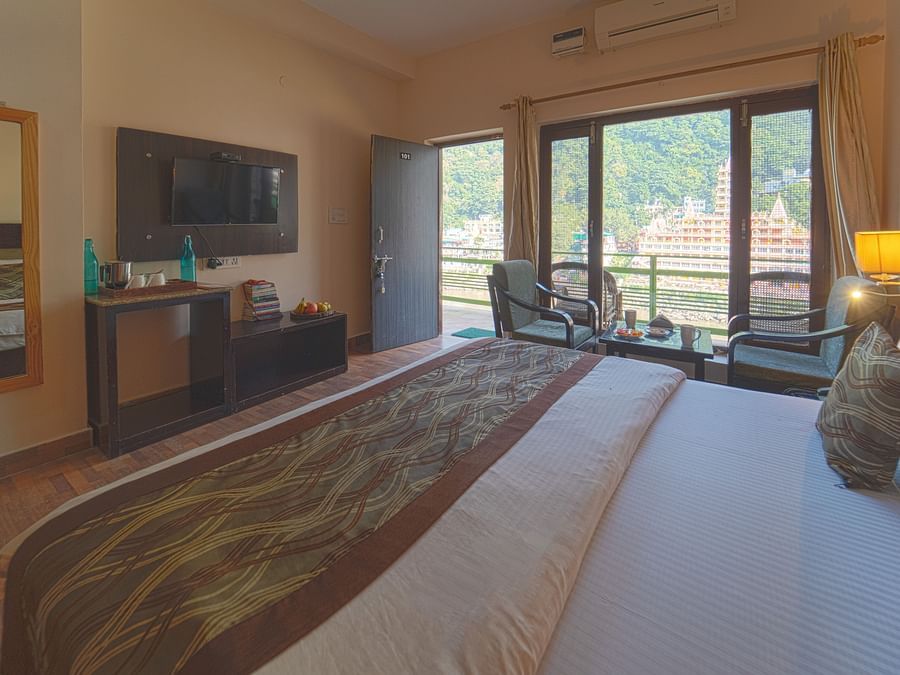 View of Deluxe Room with plush bed, large windows overlooking Laxman Jhula - Kunwar Residency