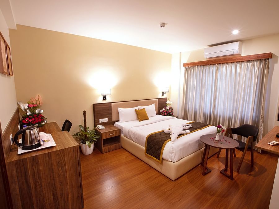 Wooden workstation with a tea/coffee setup, wall art, and a comfortable chair - RK Gardenia, Surya City.