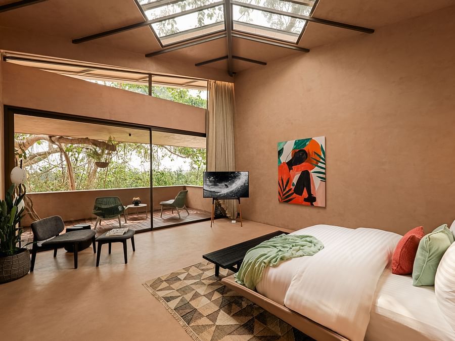Spacious bedroom with skylight ceiling , carpet, seating, paintings and lush views at Villa Moira.