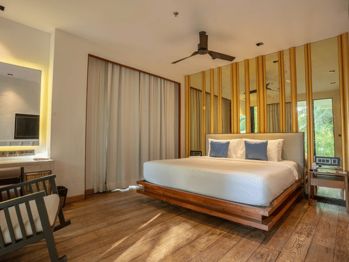 A contemporary bedroom at Azaya Beach Resort Goa featuring a floating wooden bed, timber wall panelling, and soft neutral tones.