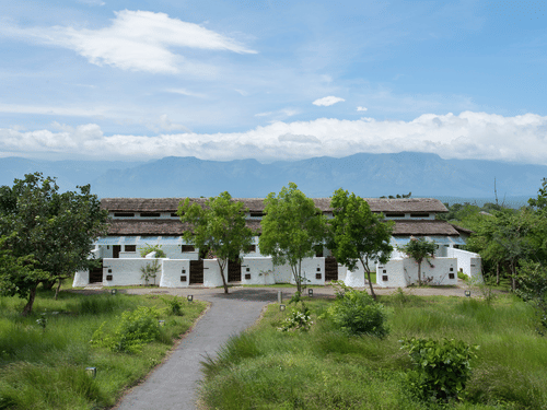 Facade of The Serai Bandipur with buildings surrounded by trees, the perfect place for a Bandipur night stay.
