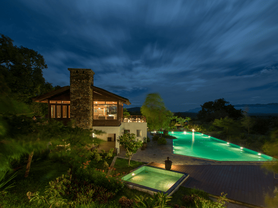 An overview of the swimming pool with the lights on as seen during twilight hour at The Serai Bandipur.