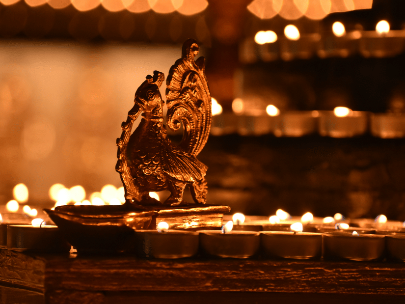 Ornate brass lamp surrounded by rows of glowing diyas in a festive setting