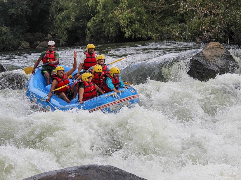  A raft with six people in safety gear navigating through a rough river, showing intense concentration and teamwork in an exhilarating environment.