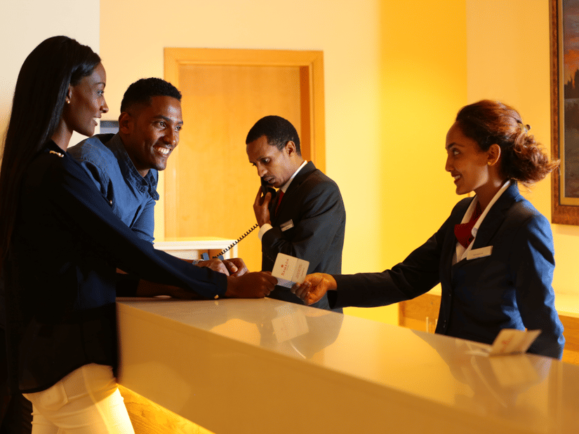An overview of the reception area with a staff member speaking to two customers - Ramada by Wyndham Addis, Addis Ababa.