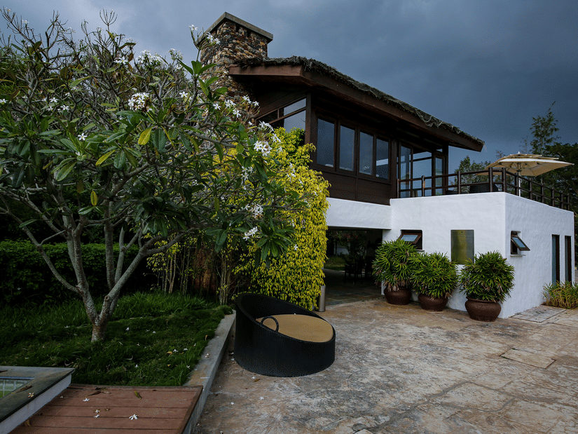The exterior facade of a cottage with shrubs next to the building at The Serai Bandipur, unlike any other hotels in Bandipur.