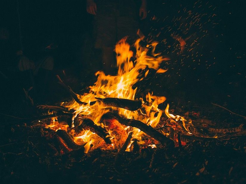 A close up shot of a bonfire with the fire raging on the wood