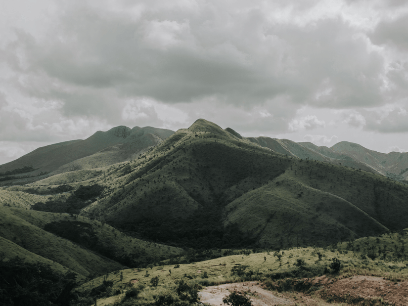 Panoramic view of the rolling green hills of Baba Budangiri in Chikmagalur under a dramatic cloudy sky.