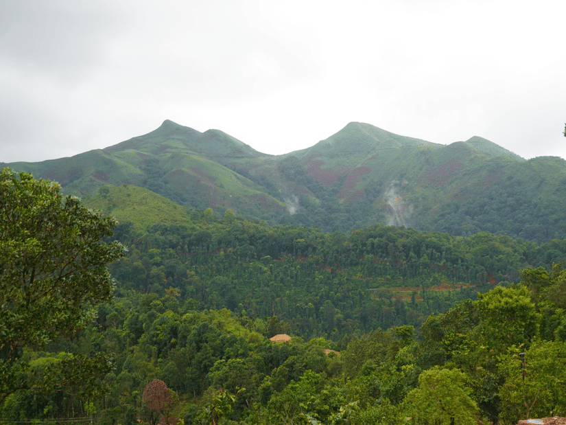 Mountains in Chikmagalur featuring lush slopes under a partially cloudy sky