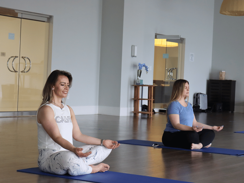A couple of women meditating indoor on their respective yoga mats with their eyes closed at YO1 Longevity and Health Resort