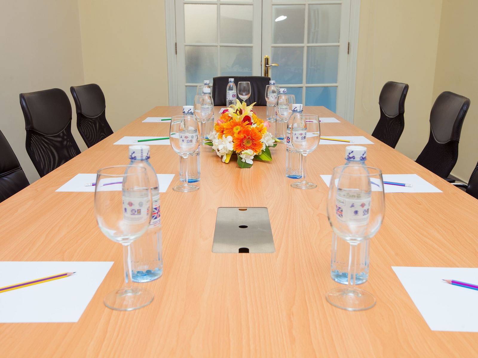 A meeting room with a long table, chairs, and glasses | Conference Hall | Central Mansions, Phnom Penh