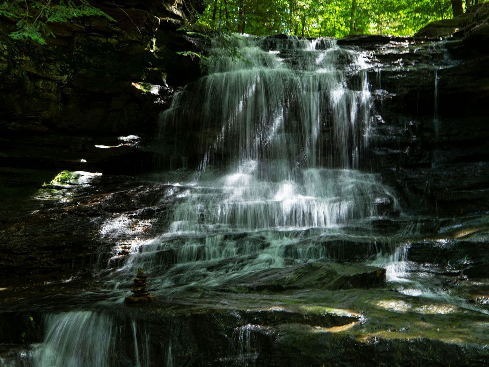 An image of a waterfalls surrounded by lush greenery