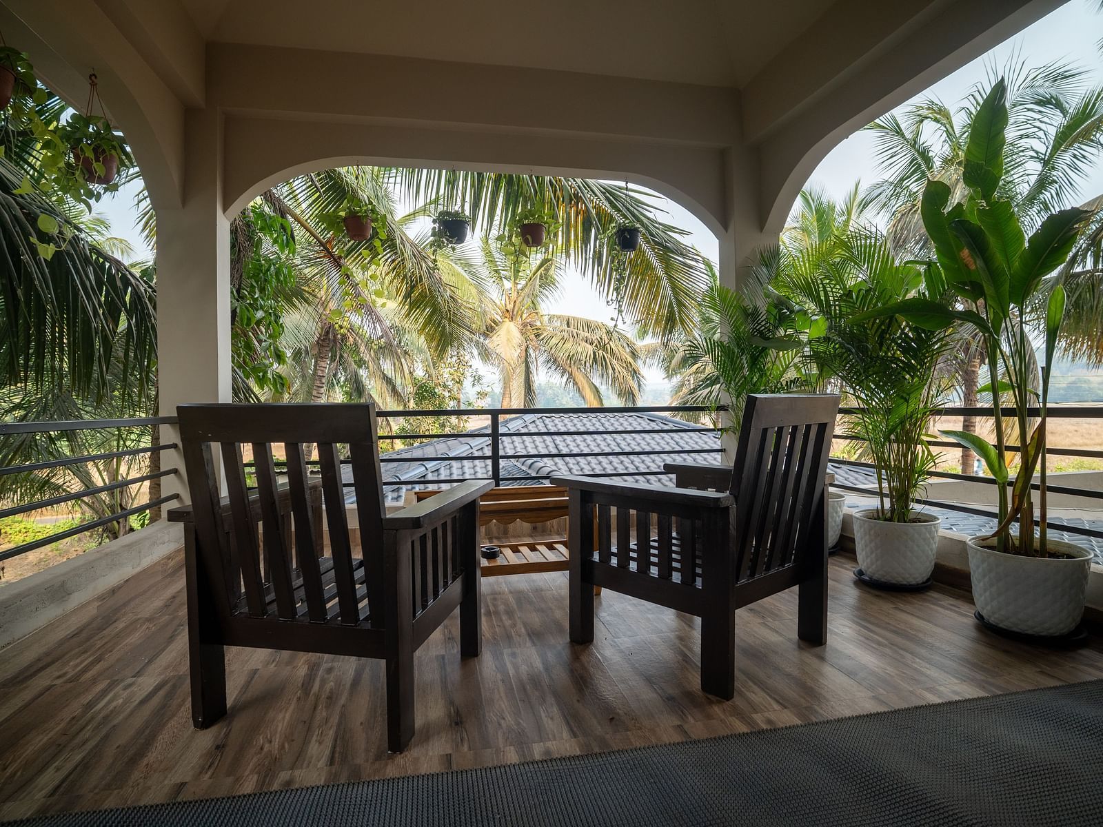 Tropical balcony setup with wooden seating and lush coconut trees view at Kssemya.