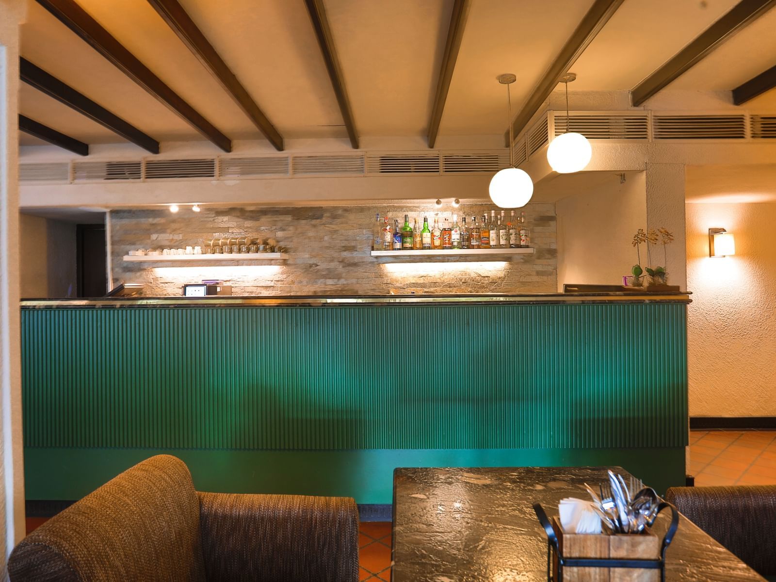 A cosy bar at Shilton International, Kochi, with a well-stocked counter and comfortable seating, ideal for relaxation.