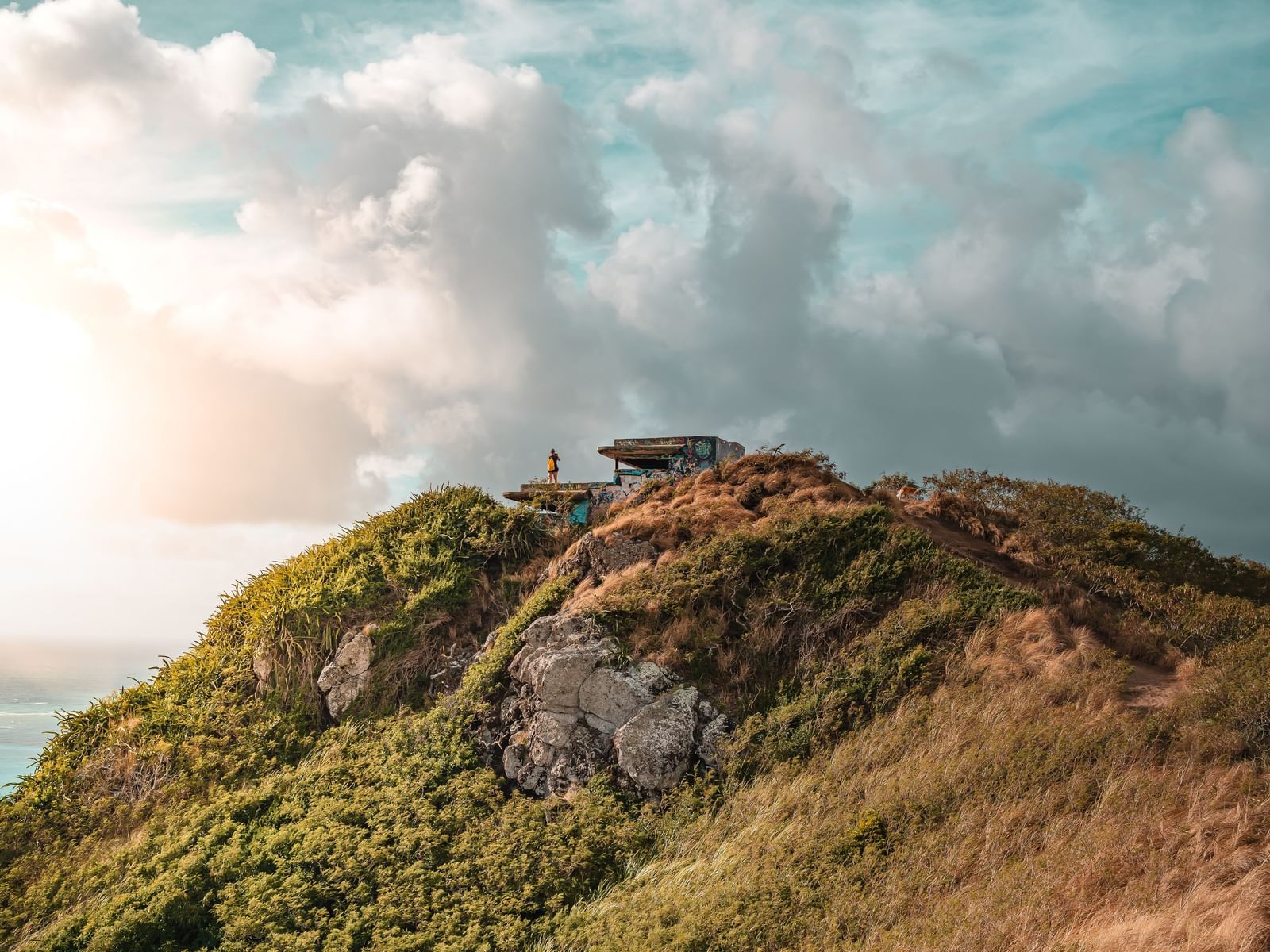 person on top of hill under a cloudy sky