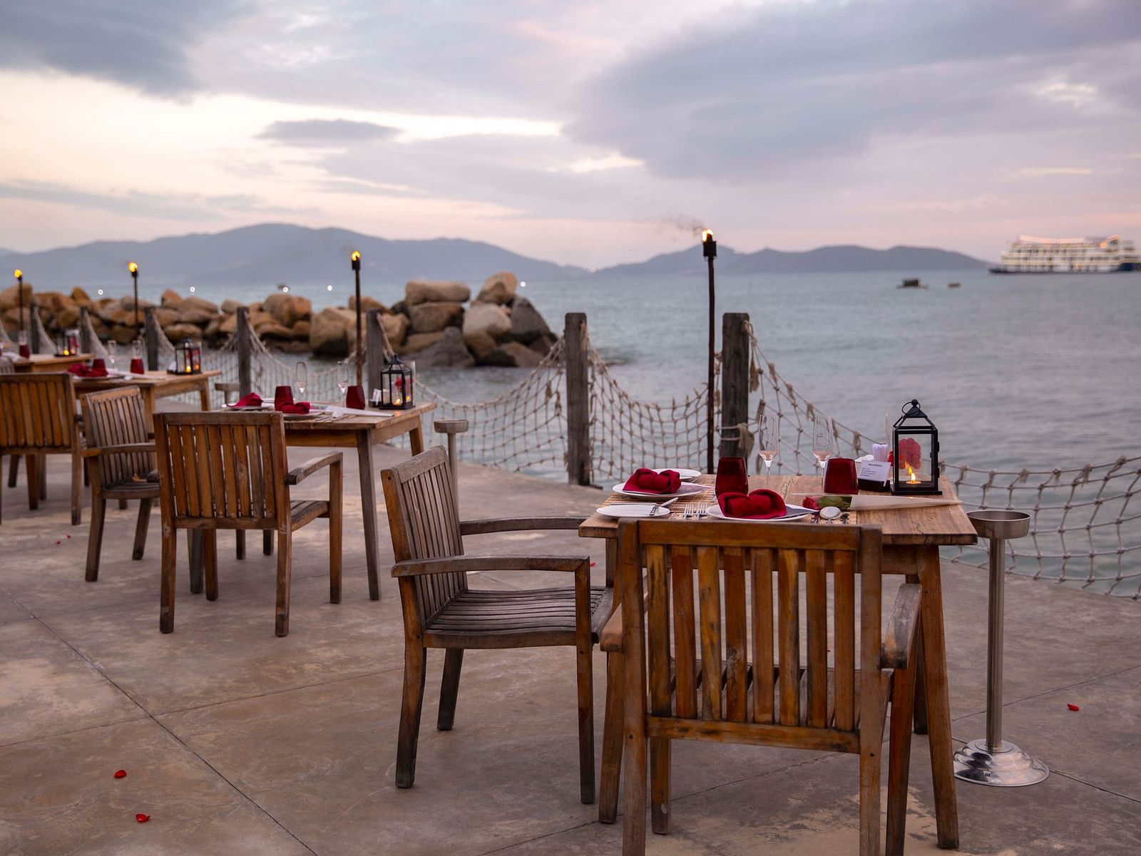 An array of tables arranged by the Nah Trang bay seen during a serene sunset - Alibu Resort Nha Trang