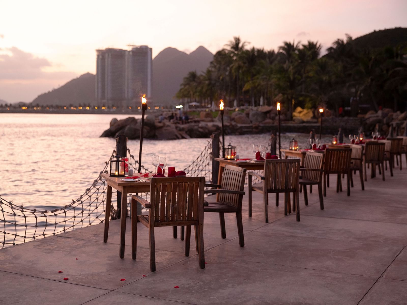 A serene sunset view by the Nah Trang bay with furniture arranged near the ocean - Alibu Resort Nha Trang