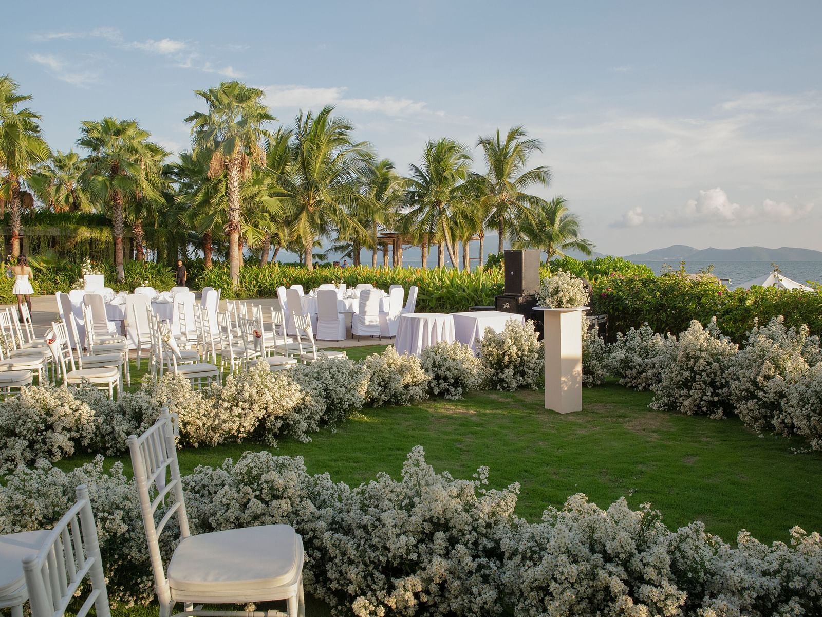 A lawn near the bay with white chairs - Alibu Resort Nha Trang