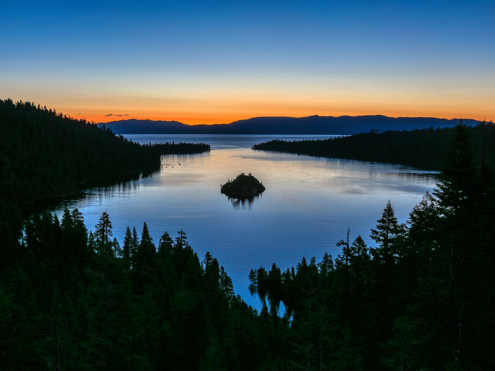 Emerald Bay at sunset, with the golden light reflecting on the water surrounded by trees