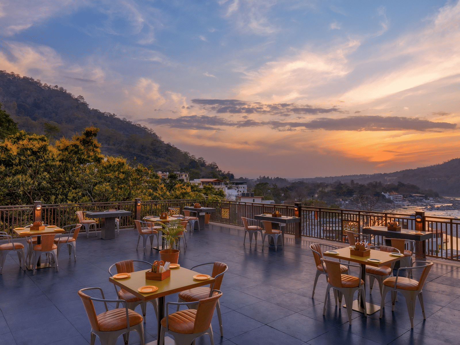 A cluster arrangement with tables and chairs on a terrace with mountain views during the sunset - Bedzzz, Rishikesh