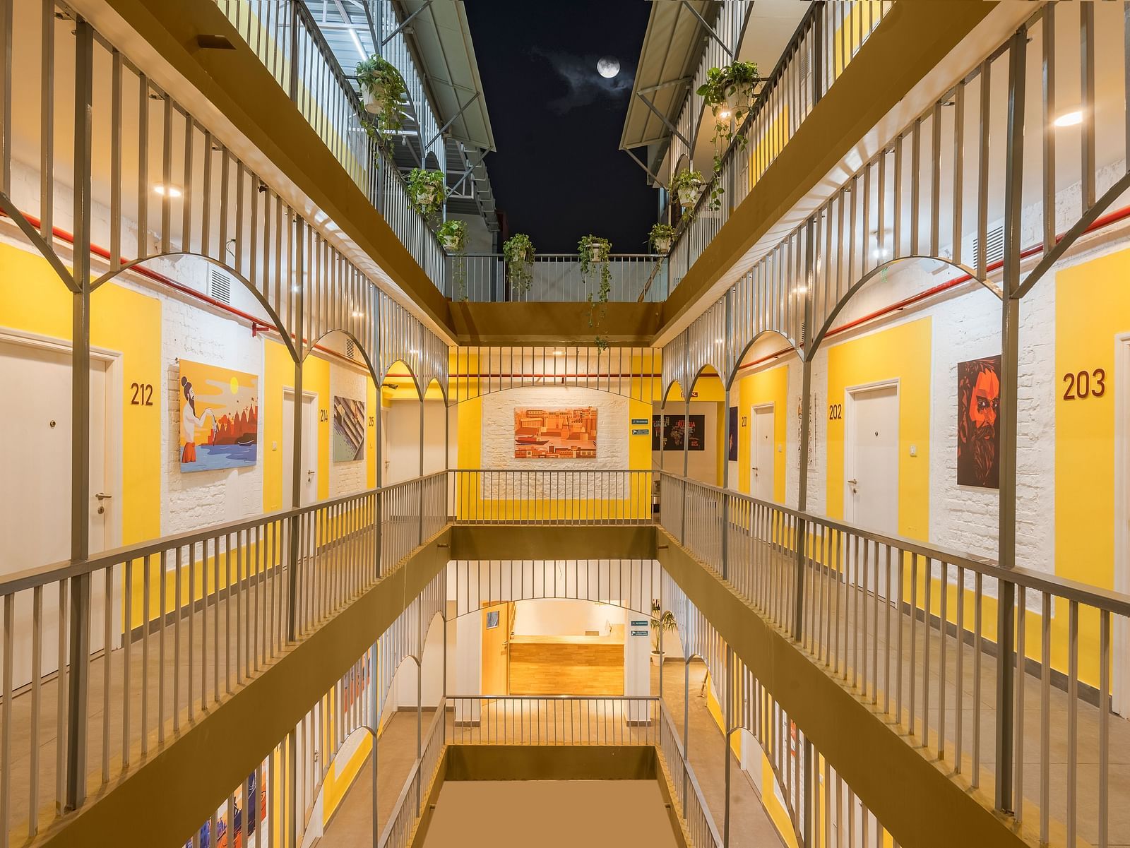 An image of the corridor at Bedzzz Varanasi, brightly lit, with a few wall paintings hanging on the walls, captured in the night.