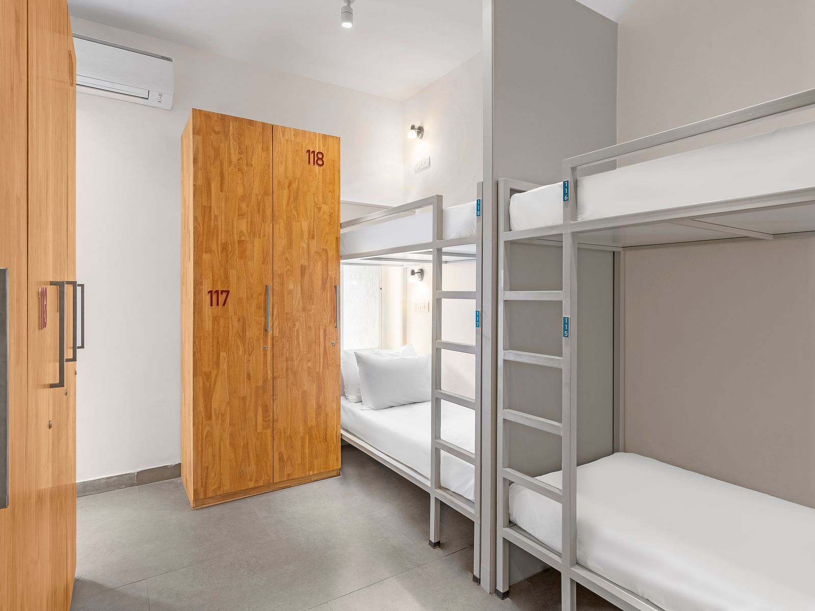 Dorms at Bedzzz in Varanasi feature a practical layout with built-in cupboards and a door, ensuring privacy and ample storage space. The design creates a comfortable environment for guests, making it an ideal choice for travelers seeking a cozy stay.