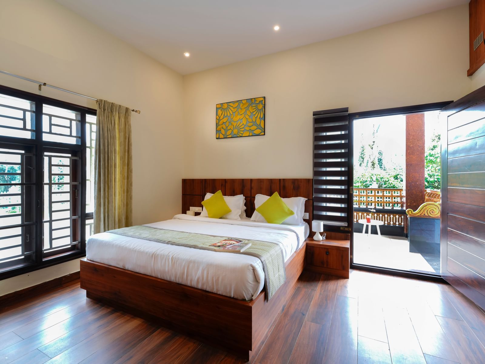  A premium room at Bhuthanakadu Retreat, featuring a large wooden bed with bright green and white bedding, and a sliding glass door leading to a balcony.