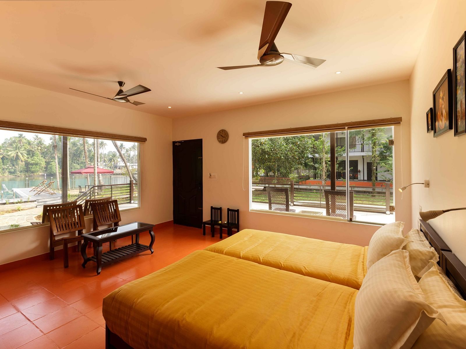 A bedroom with two beds, a seating area by a window, and ceiling fans.