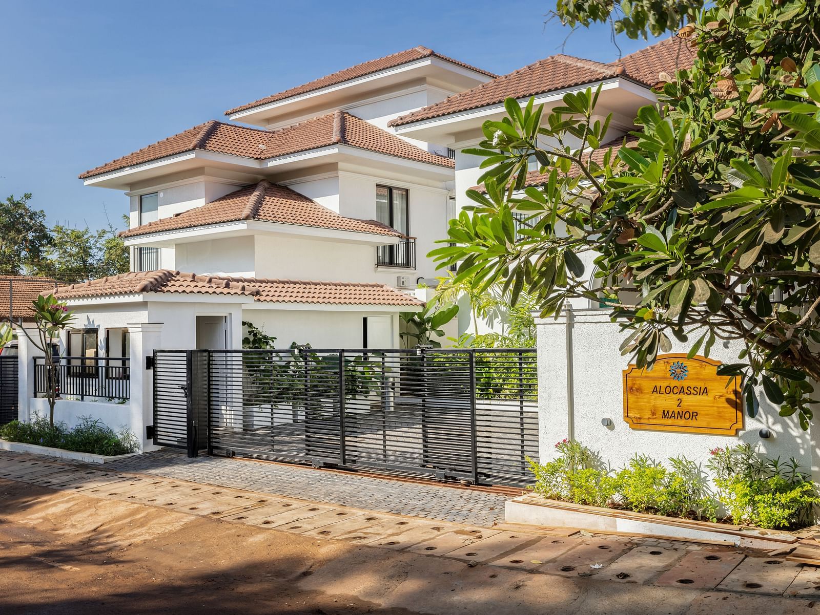 A side view of a modern villa with a landscaped garden, gated entrance, and stylish design elements - BluSalzz Villas - Alocassia, Anjuna