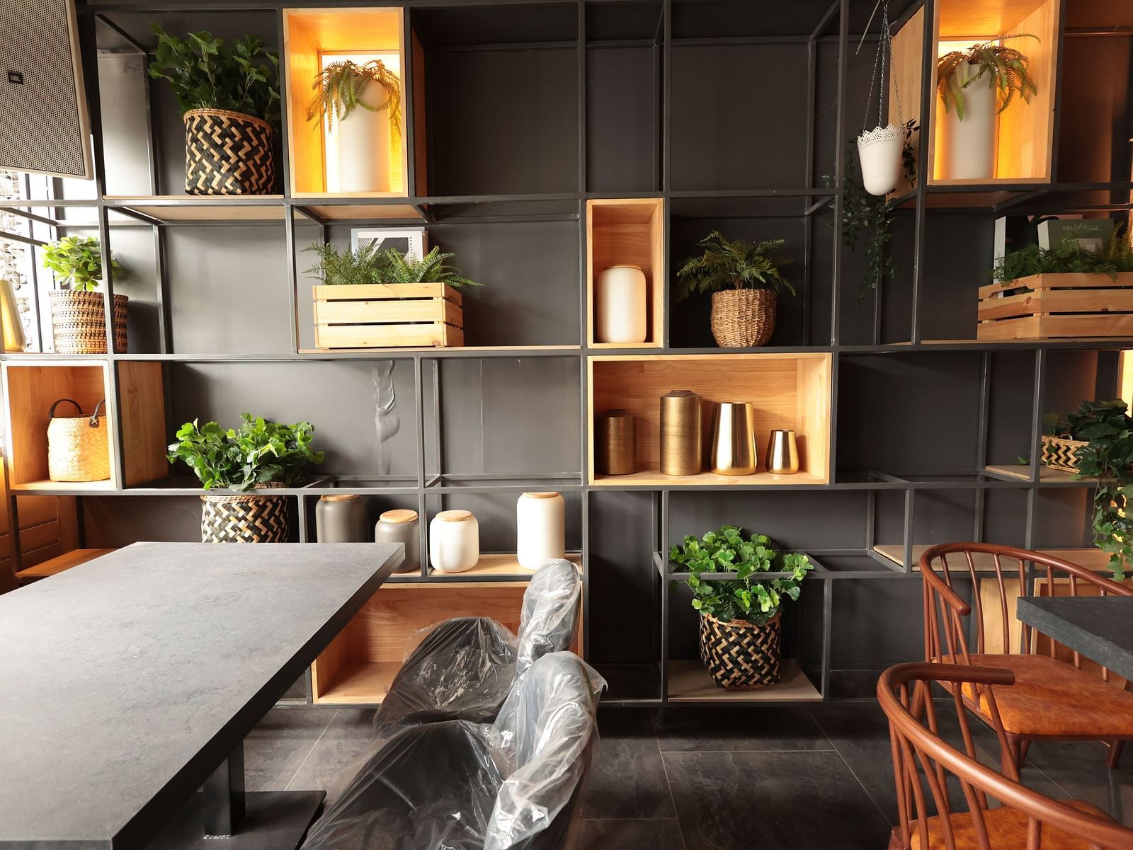 A spacious dining area with a background shelf decorated with plants, pots, and vessels | Cenneys Gateway