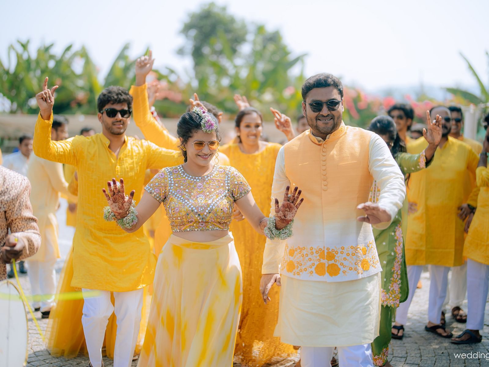 image featuring the couple with their freinds and family dancing in the background with yellow colour as the dress code at darza resorts