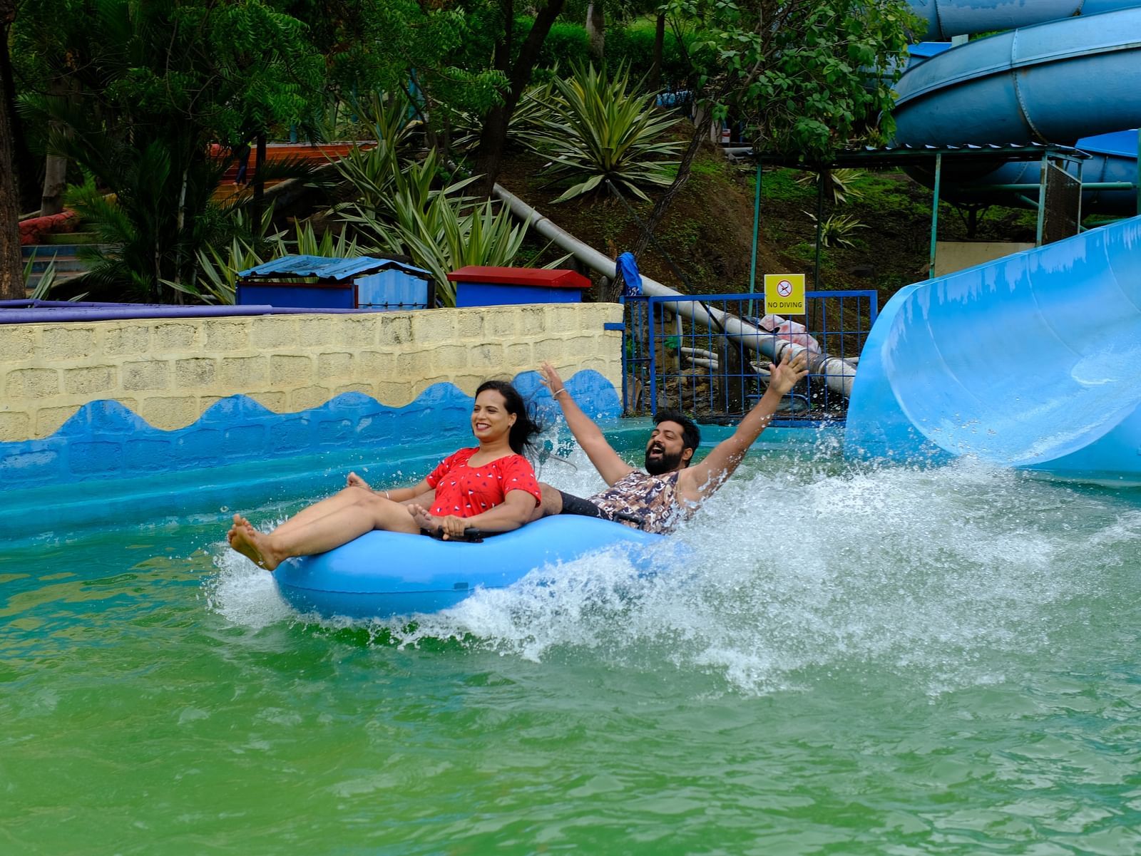 couple having fun on a water slide in a rubber raft at an adventure water park | Diamond Parks, Pune 