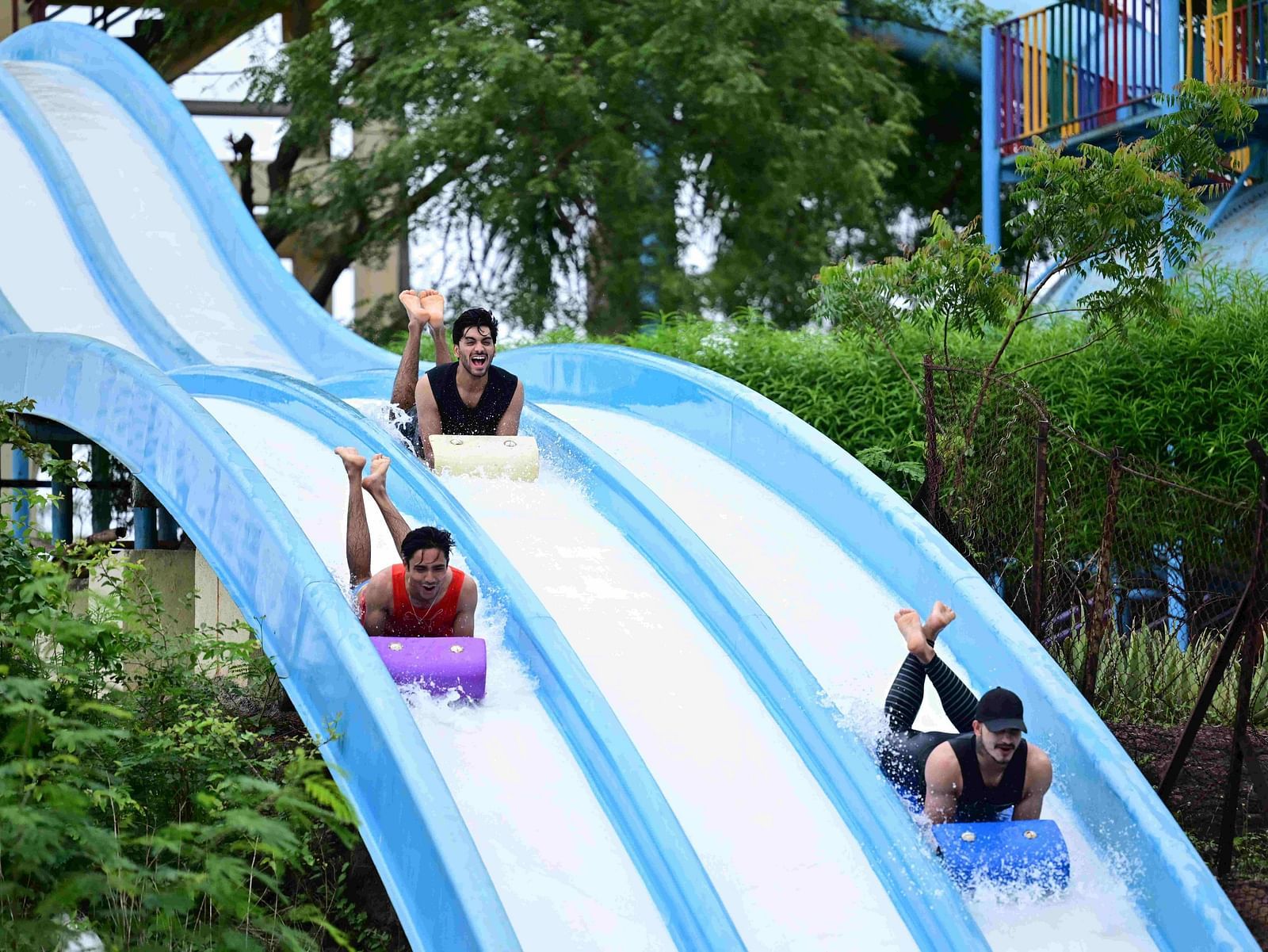 people sliding down a multi-lane water slide at an amusement park | Diamond Parks, Pune 