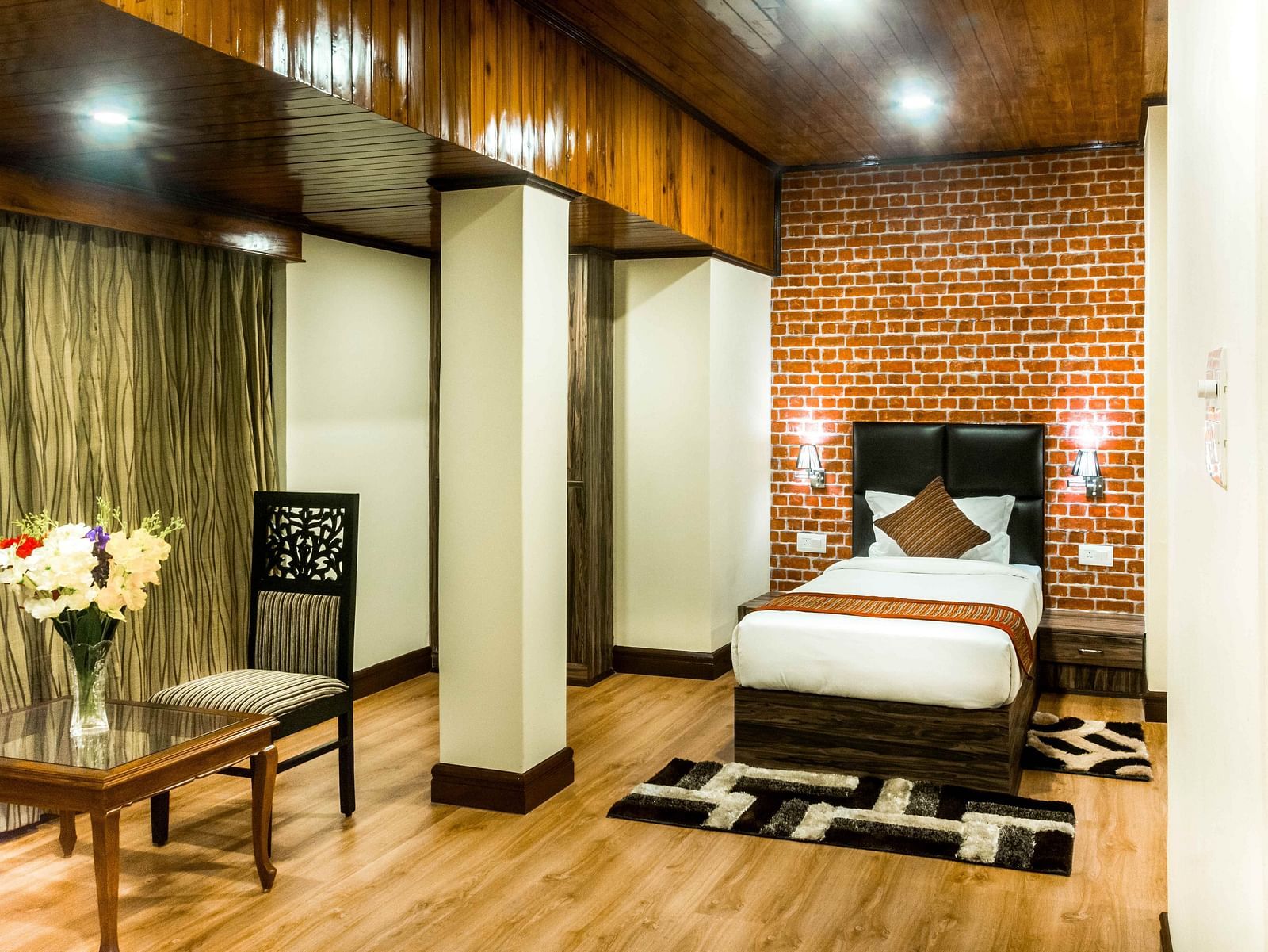 An image of a suite at the Ecotel Tin Tin, Bijanbari featuring a single bed, bed side tables, a table and a chair and other amenities