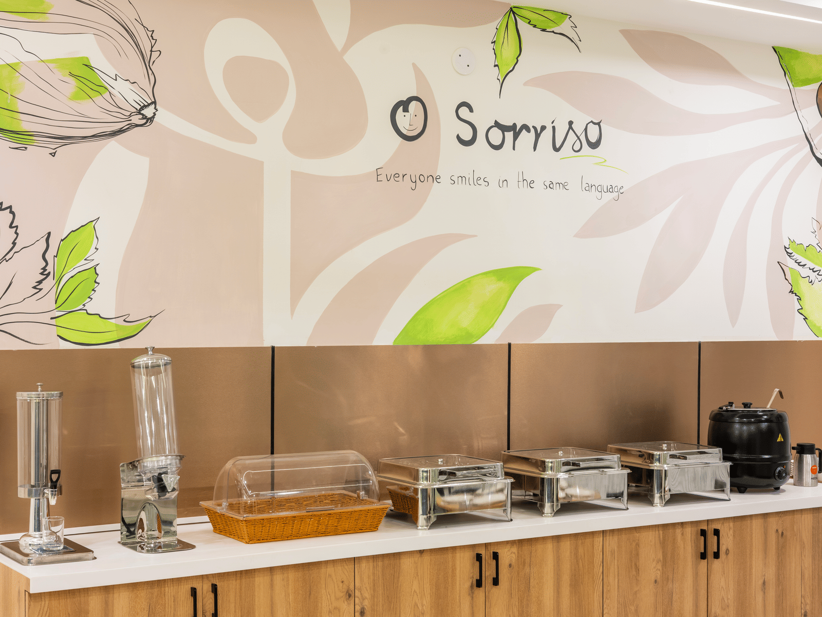 A buffet area with food warmers and a wall graphic at Elysium Studio Suites, Madhapur, shows food service equipment.