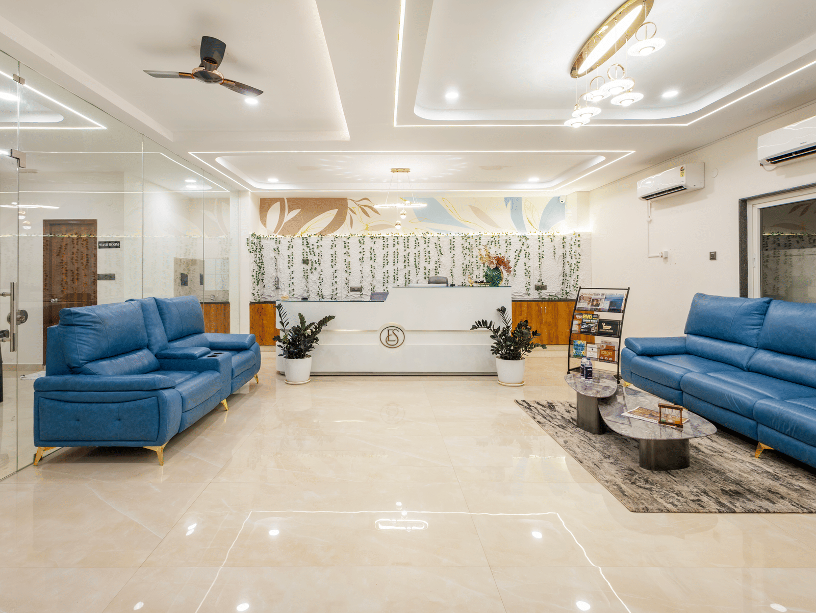 A living room at Elysium Studio Suites, Madhapur, contains blue sofas and light fixtures on the ceiling.