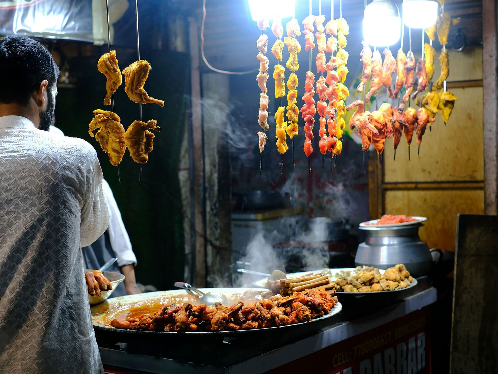 An overview of a street stall with skewered meat hung and marinated meat kept on the pan.