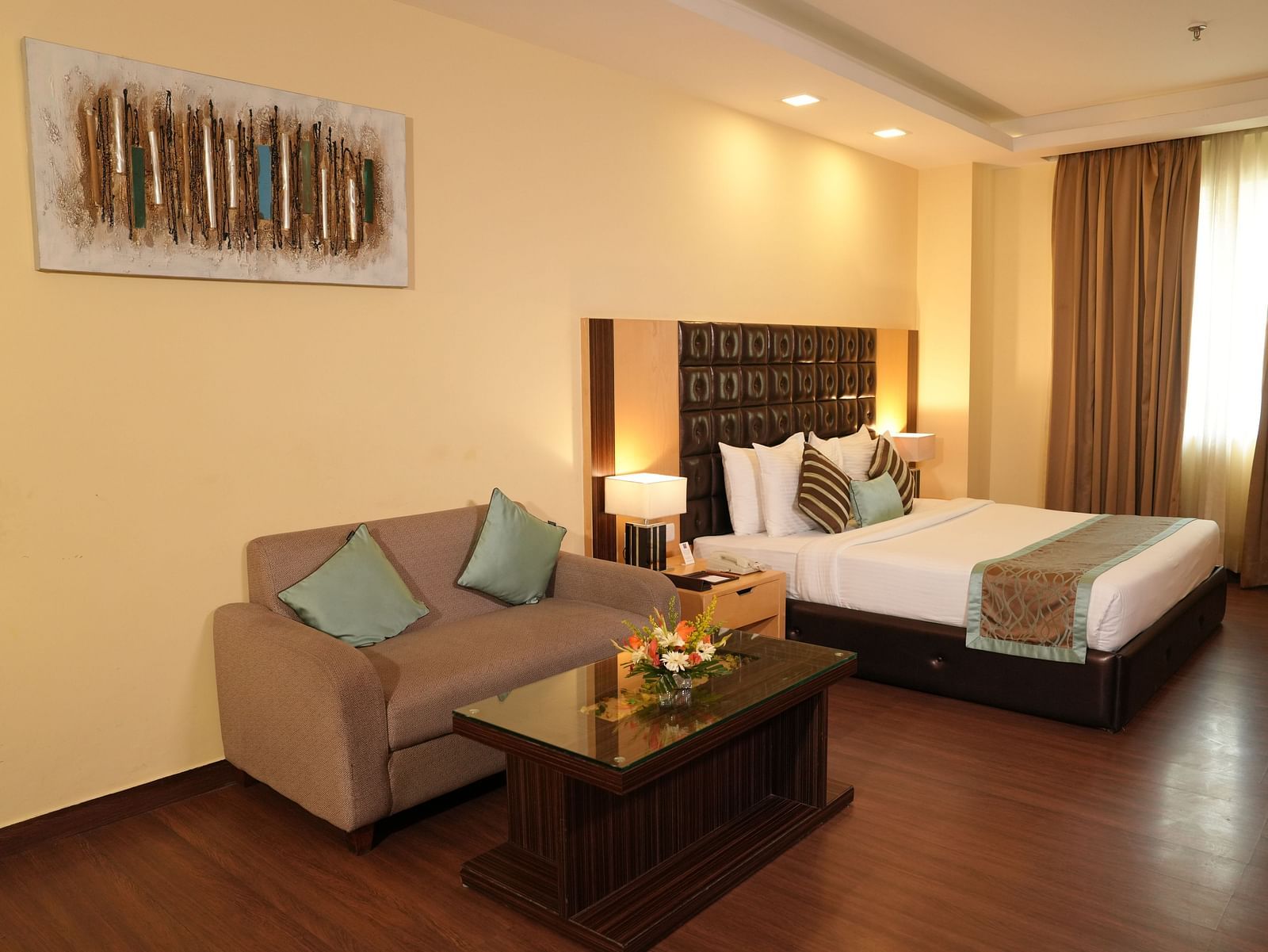 Spacious hotel room with a bed, seating area, and large window - Grand Plaza Lords Inn Jammu