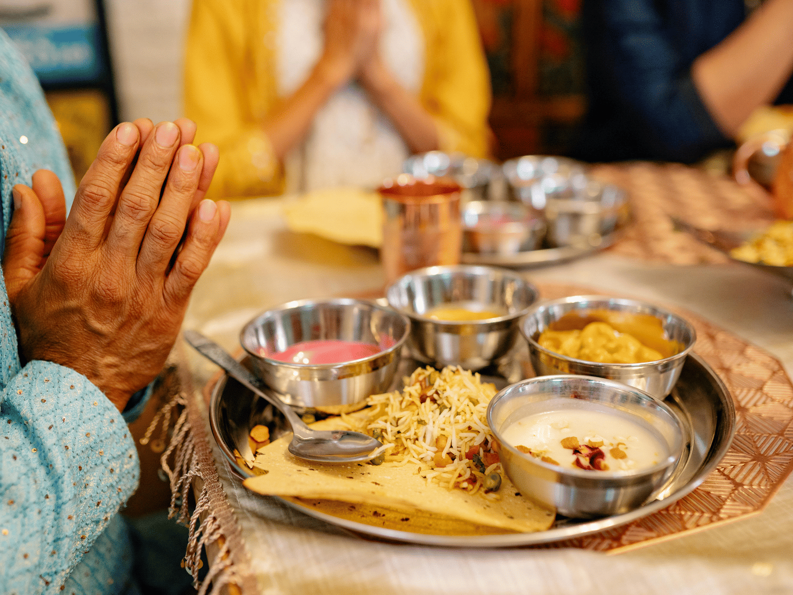 A traditional Indian wedding ritual setup with plates of offerings, flowers, and hands joined in prayer during the ceremony.